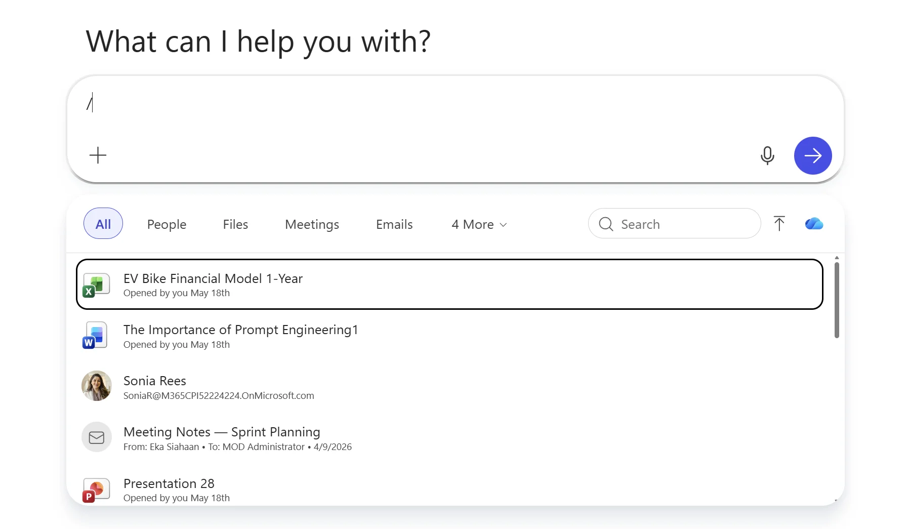 Microsoft 365 Copilot Chat composer with just a slash character typed. Below the composer is the slash picker panel showing tabs at the top — All (selected, highlighted blue), People, Files, Meetings, Emails, and 4 More dropdown — plus a search box and an upload arrow icon on the right. Five mixed-type results are visible: an Excel file EV Bike Financial Model 1-Year, a Word document The Importance of Prompt Engineering1, a person Sonia Rees with email address, an Email titled Meeting Notes Sprint Planning from Eka Siahaan, and a PowerPoint file Presentation 28. Each result shows a Microsoft 365 app icon, the title, and metadata such as Opened by you May 18th.